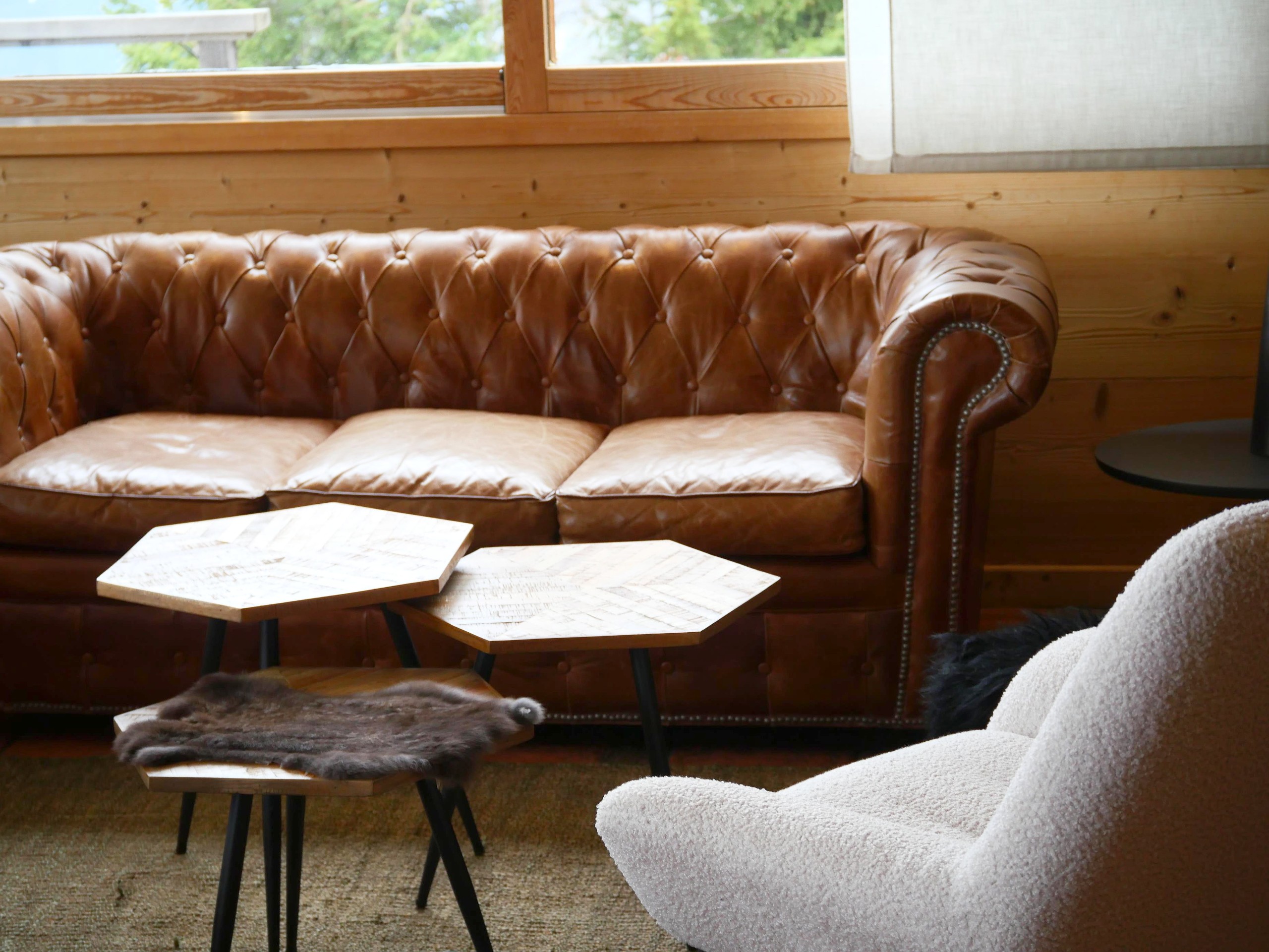 Coin salon : canapé Chesterfield en cuir et fauteuil en laine bouclée