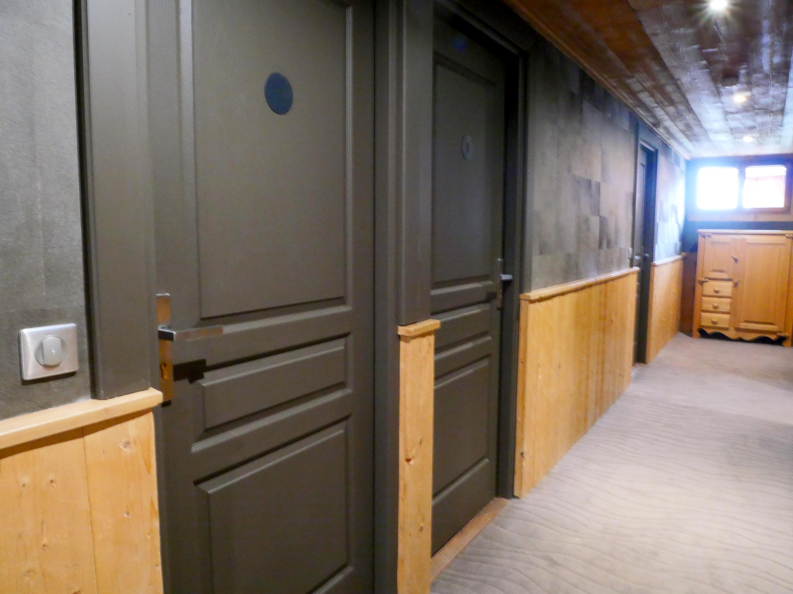 Couloir des chambres : portes grises et soubassements en bois