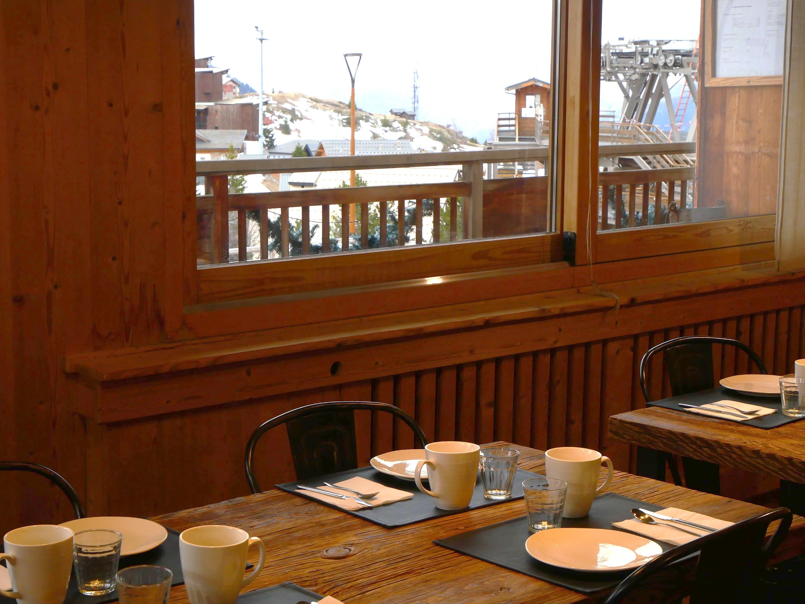 Tables du petit-déjeuner dressées près de la fenêtre, vue sur la station