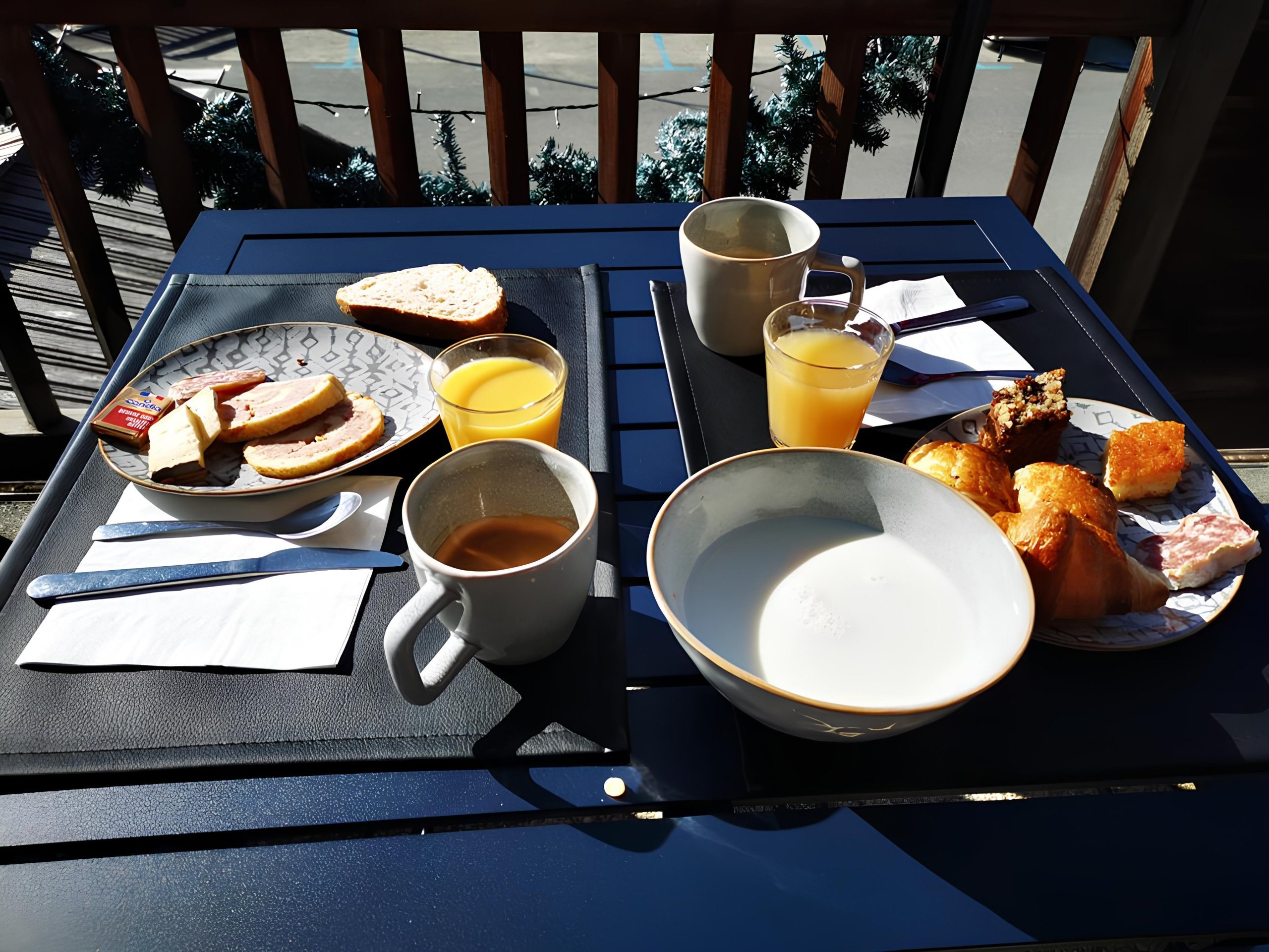 Petit-déjeuner servi en terrasse, au soleil : viennoiseries, jus d'orange et café